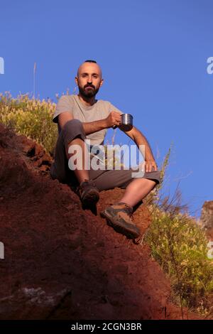 Stolzer junger hispanischer Wanderer ruht auf dem Gipfel Stockfoto