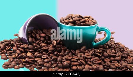 Tassen Kaffee mit Bohnen in und verschüttet herum mit Pastellfarben Stockfoto