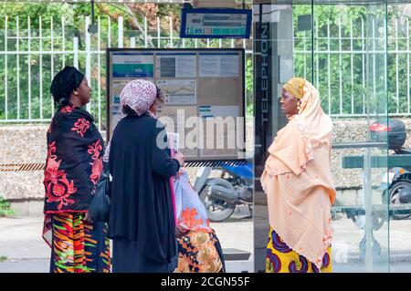 Paris, Frankreich - 02. Oktober 2013: Drei afrikanisch-muslimische Frauen in traditioneller Kleidung warten an einer Bushaltestelle in den Außenbezirken von Paris, Frankreich. Stockfoto