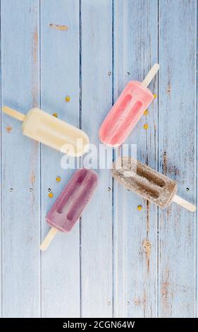 Traube, Erdbeere; Schokolade, Vanille-Popsicle auf blauem Hintergrund rustikal Stockfoto