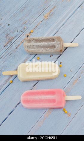 Erdbeere; Schokolade, Vanille-Popsicle auf blauem Hintergrund Rustikal Stockfoto