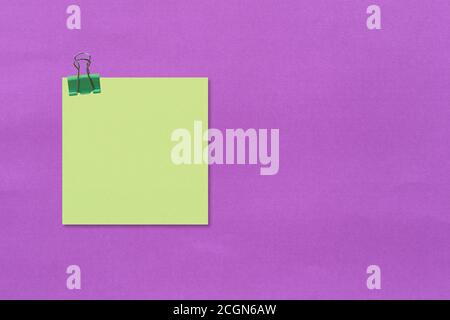 Papier auf violettem Hintergrund notieren und Büroklammer verwenden. Stockfoto