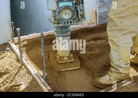 Arbeiter mit Vibrationsplatte Verdichter Sandbau neuen Gehweg verdichten Stockfoto