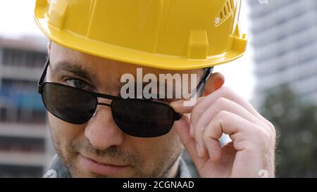 Junger schöner Ingenieur Mann trägt Schutzhelm in Sonnenbrille Stockfoto