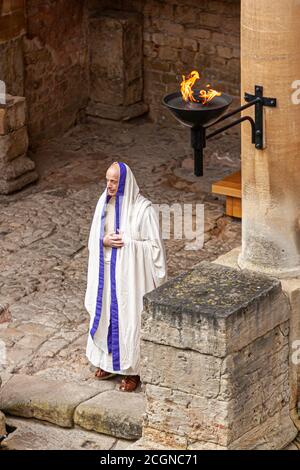 Bath, UK, 03/06/2010: Ein älterer kaukasischer Mann, der im antiken Rom wie ein Priester verkleidet ist, steht in einem historischen römischen Gebäude. Das Steingebäude h Stockfoto