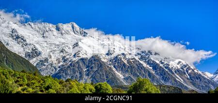 Panoramablick die hohen Berge an der Spitze sind Schnee und Wolken. Am Morgen blauer Himmel im Mount Cook National Park, Aoraki, Neuseeland Stockfoto