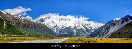 Spektakulärer Panoramablick auf die Berge in der Sommersaison im Mount Cook Nationalpark in Neuseeland. Eine gerade Straße, die zu einem großen Berg führt. Stockfoto