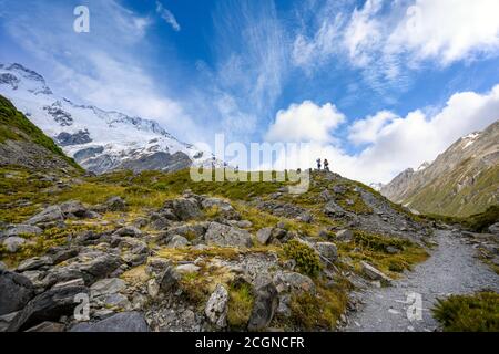 Zwei Touristen stehen auf dem Hügel, um Panoramabilder des Müller-Gletschers am Kea Point im Mount Cook Nationalpark, der felsigen Berge und zu machen Stockfoto