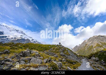 Zwei Touristen stehen auf dem Hügel, um Panoramabilder des Müller-Gletschers am Kea Point im Mount Cook Nationalpark, der felsigen Berge und zu machen Stockfoto