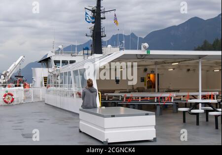 Vancouver, Kanada - 16. Juli 2020: Junge Frau auf leerem Sonnendeck der BC Ferry, was die Anzahl der Passagiere aufgrund von COVID-19 begrenzt Stockfoto