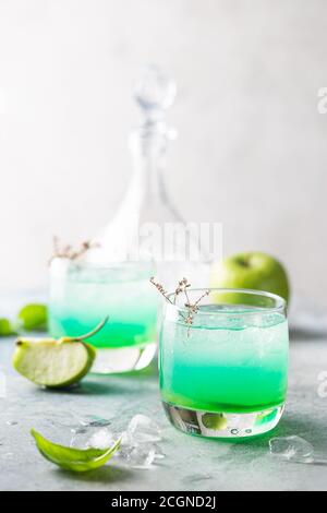 Grüner Cocktail mit Äpfeln auf weißem Hintergrund, martini-Cocktail in Gläsern Stockfoto