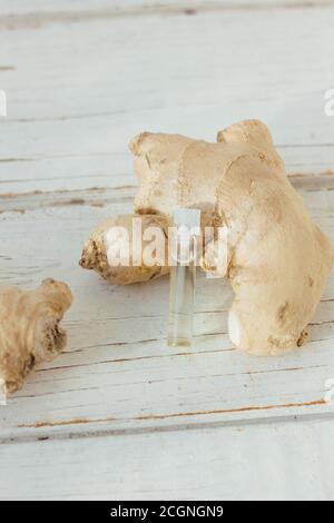 Ingwer ätherisches Öl in Glasflasche mit Ingwerwurzel dahinter Stockfoto