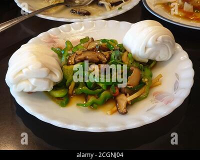 Chinesisches Pfeffersteak und geblümte Brötchen. Braten Sie das Gericht mit zarten Scheiben von Rindfleisch und Paprika in einer dicken herzhaften Sauce. Stockfoto