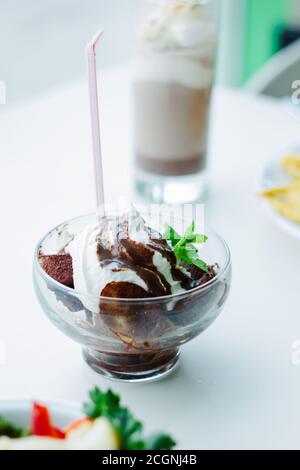 Schöne Bananen- und Schokoladendessert in einer Glasschale auf weißem Tisch Stockfoto