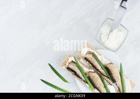 Kochen von gesunden Nord traditionelle Sandwiches von trockenen Chips Weizenbrot mit Sprossen Fisch, Frischkäse, grüne Zwiebel auf weichen hellen weißen Holz Backgro Stockfoto