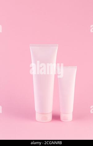 Zwei kosmetische Tuben Paket auf pastellrosa Hintergrund. Leere Kunststoffbehälter, einfache Verpackungsdesign-Vorlage. Geringe Schärfentiefe, Kopierraum p Stockfoto