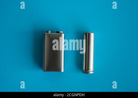 9-V-Hochvolt-Batterie und AA-Alkali-Mangan-Batterie auf blauem Hintergrund. Energie. Stockfoto