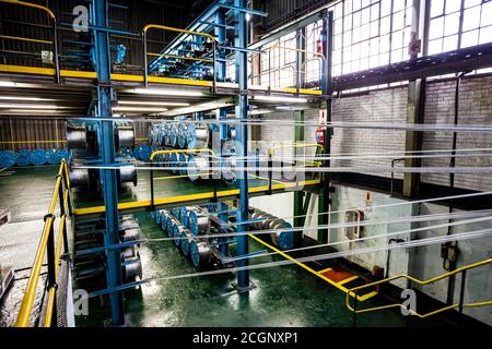 Johannesburg, Südafrika - 16. Oktober 2012: Weitwinkelansicht von Kabelspulen auf einer großen Maschine in einer Förderbandfabrik Stockfoto