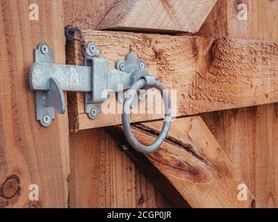 Ein silberner Bolzen sichert ein Holztor in einem Garten Stockfoto