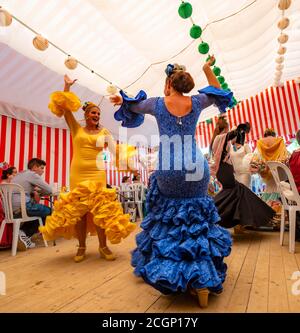Frauen tanzen Sevillano, Spanierin mit Flamenco-Kleidern in bunten Festzelt, Casetas, Feria de Abril, Sevilla, Andalusien, Spanien Stockfoto