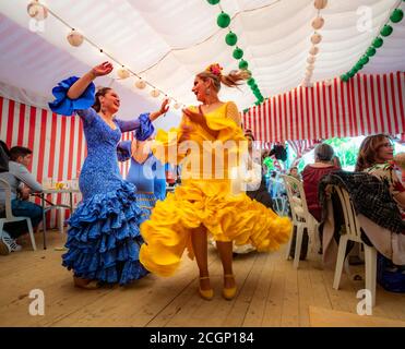 Frauen tanzen Sevillano, Spanierin mit Flamenco-Kleidern in bunten Festzelt, Casetas, Feria de Abril, Sevilla, Andalusien, Spanien Stockfoto