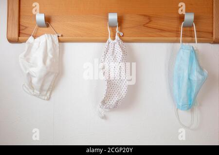 Verschiedene Corona-Schutzmasken hängen an Kleiderhaken, Einwegmaske und Stoffmaske, Nordrhein-Westfalen, Deutschland Stockfoto