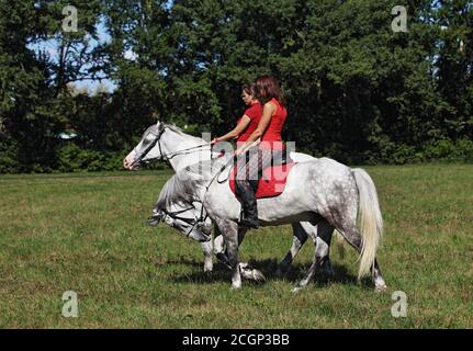 Zwei Mädchen, die auf dem Rücken eines andalusischen Paares reiten Stockfoto