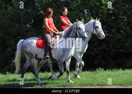 Zwei Mädchen, die auf dem Rücken eines andalusischen Paares reiten Stockfoto