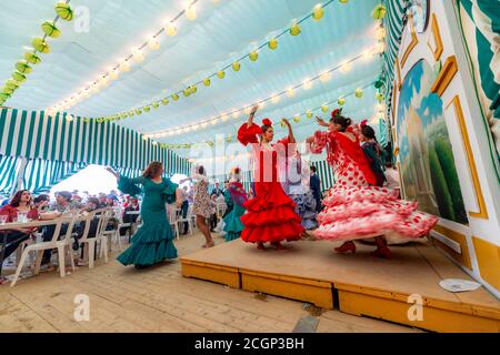 Junge Frau, die Sevillano tanzt, Spanierin mit Flamenco-Kleidern im bunten Festzelt, Casetas, Feria de Abril, Sevilla, Andalusien, Spanien Stockfoto