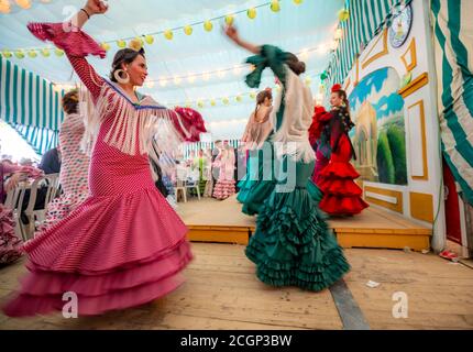 Junge Frau, die Sevillano tanzt, Spanierin mit Flamenco-Kleidern im bunten Festzelt, Casetas, Feria de Abril, Sevilla, Andalusien, Spanien Stockfoto
