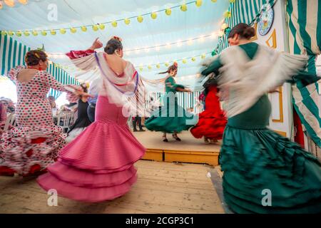 Junge Frau, die Sevillano tanzt, Spanierin mit Flamenco-Kleidern im bunten Festzelt, Casetas, Feria de Abril, Sevilla, Andalusien, Spanien Stockfoto