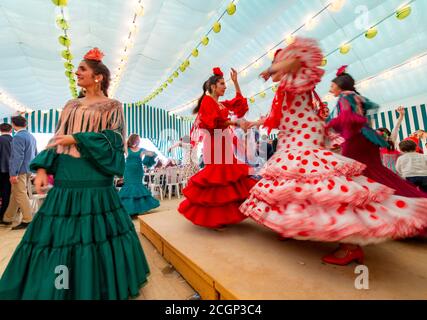 Junge Frau, die Sevillano tanzt, Spanierin mit Flamenco-Kleidern im bunten Festzelt, Casetas, Feria de Abril, Sevilla, Andalusien, Spanien Stockfoto