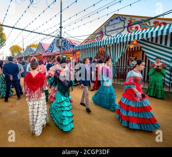 Frauen in bunten Flamenco-Kleidern, vor Festzelten, Casetas, geschmückte Straße, Feria de Abril, Sevilla, Andalusien, Spanien Stockfoto