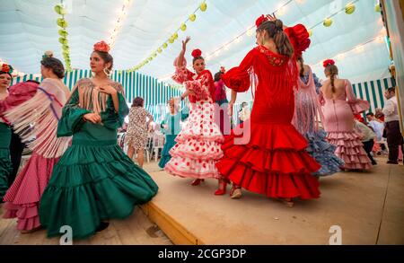Junge Frau, die Sevillano tanzt, Spanierin mit Flamenco-Kleidern im bunten Festzelt, Casetas, Feria de Abril, Sevilla, Andalusien, Spanien Stockfoto