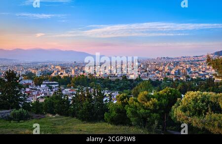 Blick auf Athen und seine Wohngebiete von Pnyx Hügel In weichem Abendsonne mit großen Sonnenuntergang Himmel Stockfoto