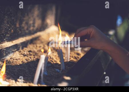 Frau, die im Garten des Hauses der Jungfrau Maria betet und Kerzen brennt. Brennende weiße Kerzen auf dem Stand. Anbetung Stockfoto