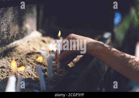 Frau, die im Garten des Hauses der Jungfrau Maria betet und Kerzen brennt. Brennende weiße Kerzen auf dem Stand. Anbetung Stockfoto