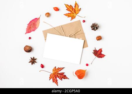 Herbstkomposition. Leere Grußkarte im Kranz aus Herbstblättern, Blumen, Nüssen, Beeren auf weißem Hintergrund. Flach liegend, Draufsicht mit Kopierraster Stockfoto