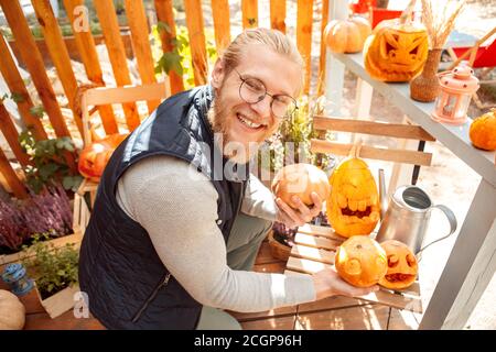 Junger Erwachsener lächelt und hält halloween Kürbisse in den Händen Stockfoto
