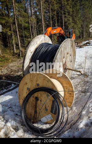 Hölzerne Rollen von elektrischen und Glasfaser-Kabel warten auf Graben zu Boden, Finnland Stockfoto