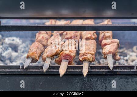 Mariniertes Grillfleisch auf Metallspieß, Schaschlik auf einem Grill über Holzkohle vorbereiten. Stockfoto
