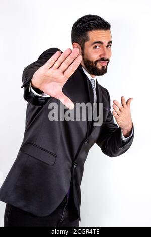 Schöner Geschäftsmann in Anzug, der herumtollt und Spaß hat. Fröhlich attraktive junge stilvolle bärtige Mann scherzte. Mittlere Aufnahme. Weißer Hintergrund. Stockfoto