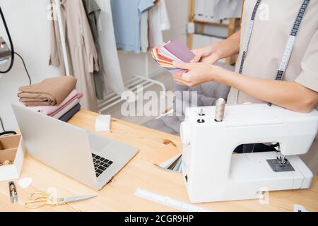 Weibliche Designer Schneiderin arbeitet an Nähmaschine im Studio. Formen Farbpalette für die Schneiderei Mode Kleidung Stockfoto