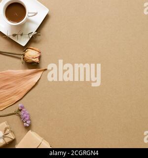 Herbstkonzept. Heißer Schokoladenkaffee mit trockenen Blumen und Geschenkbox auf braunem Kraftpapier Hintergrund. Flach legen, Draufsicht, Kopierraum Stockfoto