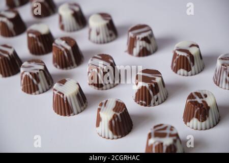 Bombone oder Bisse aus weißer Schokolade, Milchschokolade und dunkler Schokolade, gefüllt mit Haselnusscreme, Erdnussbutter und Dulce de leche. Begleitet von Stockfoto