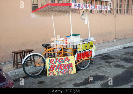 Ein Fahrrad-Food-Cart, der Fleischeintopf verkauft, der am frühen Morgen auf einer schmutzigen Straße geparkt und noch nicht für Geschäfte geöffnet ist. Stockfoto