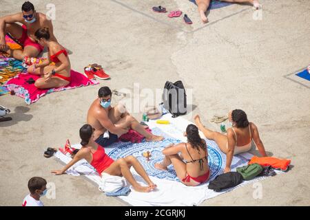 Las Palmas, Gran Canaria, Kanarische Inseln, Spanien. September 2020. Einheimische, einige mit Gesichtsmasken, sonnen sich neben natürlichen Felsenpools an der zerklüfteten Nordküste Gran Canarias, wenn Covid-Fälle auf der Insel aufsteigen, Aufgrund der kurenten Spitze bei Coronavirus-Fällen in Spanien und den kanarischen Inseln haben Großbritannien und Deutschland Spanien und die Kanarischen Inseln auf ihre Quarantäneliste gesetzt. Der Großteil der Neuinfektionen auf Gran Canaria liegt in der Hauptstadt Las Palmas. Kredit: Alan Dawson/Alamy Live Nachrichten Stockfoto