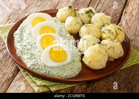 Deutsch-Stil Gericht mit Kartoffeln, gekochten Eiern und grüner Sauce close-up in einem Teller auf dem Tisch. Horizontal Stockfoto