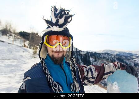 Lustige bärtige Mann Snowboarder Porträt in Mohawk Hut genießt die Skigebiet in den Bergen Stockfoto