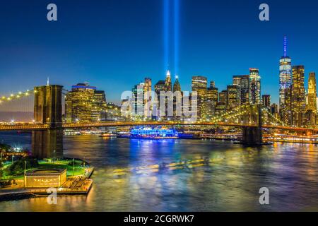 Blick auf die Skyline von Lower Manhattan und Brooklyn Brücke in der Dämmerung mit dem 11. September Tribute of Lights Glänzt über New York Stockfoto